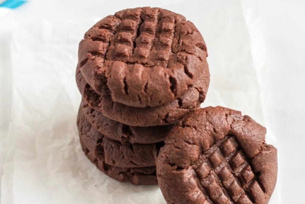 Chocolate peanut butter cookies stacked on parchment paper.