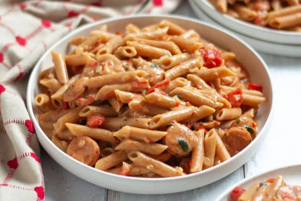 Creamy Cajun pasta with sausage on a white plate.