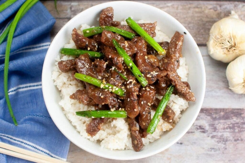 Crockpot Mongolian beef on a plate with green beans.