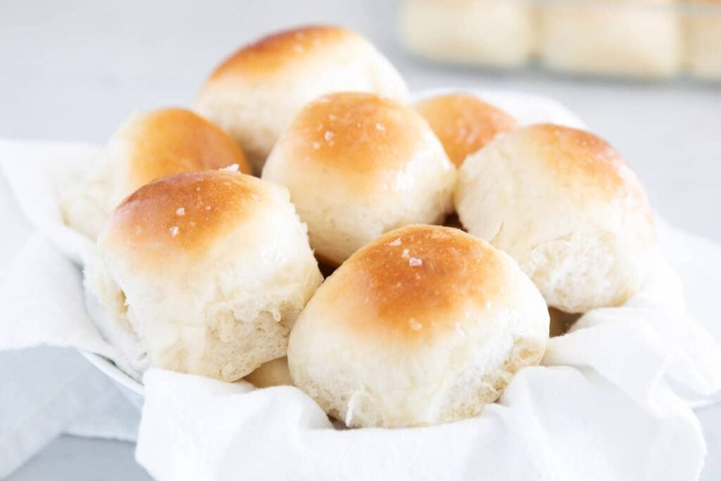 Dinner rolls in a bowl lined with a cloth.