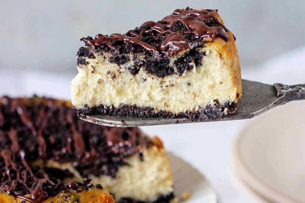 Oreo cheesecake slice lifted on a spatula.