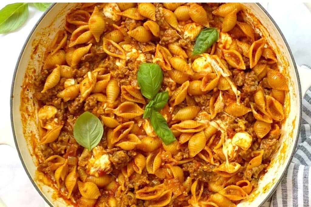 Sausage and shells in a pot.