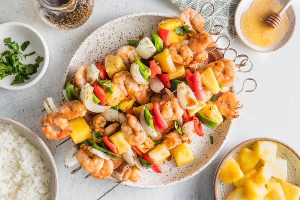 Shrimp pineapple skewers on a white plate.