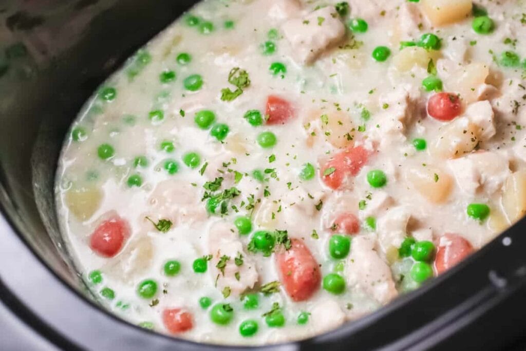 Creamy chicken pot pie with peas and carrots in slow cooker.