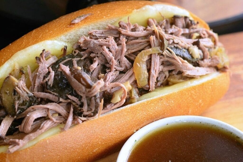 Close-up of a slow cooker mushroom and onion Italian beef sandwich.