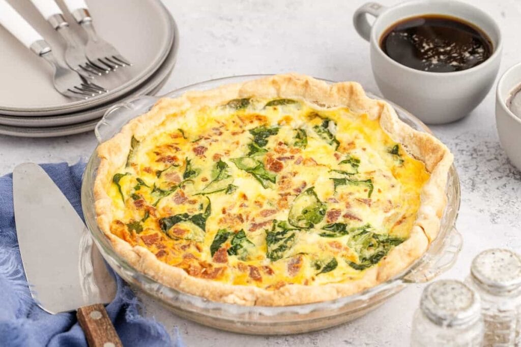 Spinach and bacon quiche on a plate.
