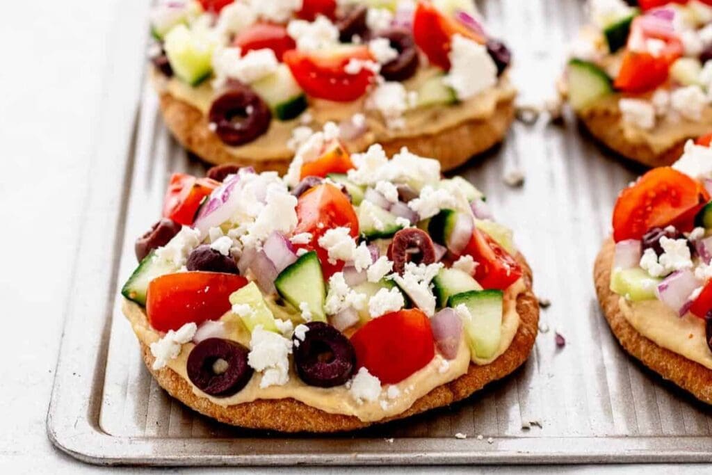 A close up shot of mini Greek pita pizzas.