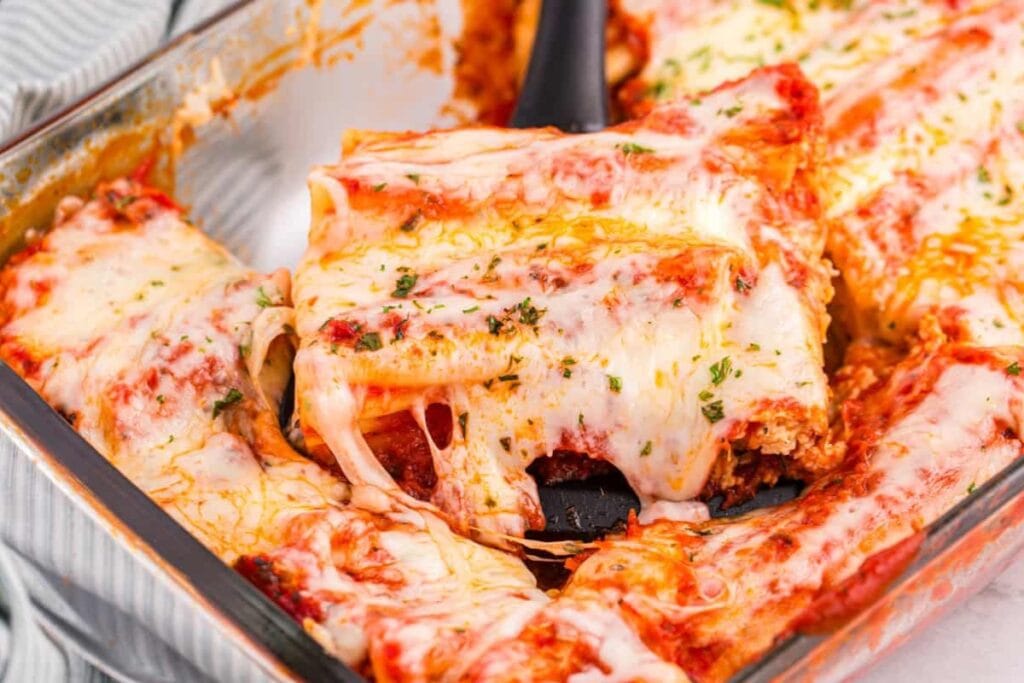 Baked manicotti with melted cheese in a baking dish.