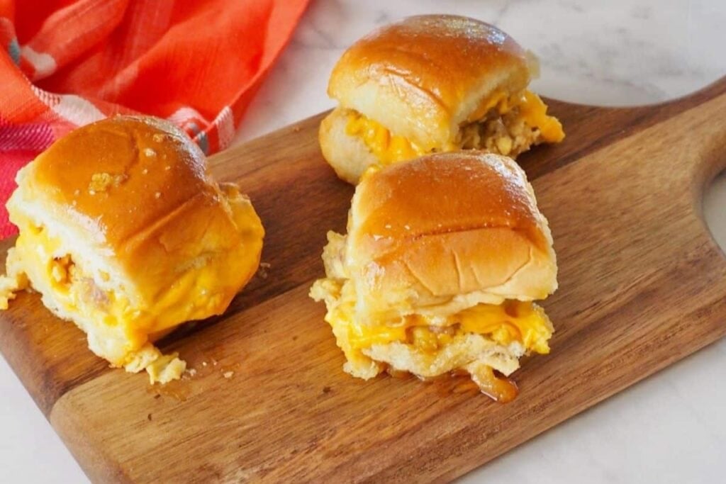 Breakfast egg sandwich sliders on a wooden board.