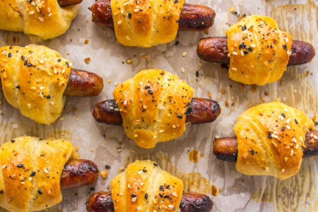 Breakfast pigs in a blanket on a baking sheet.