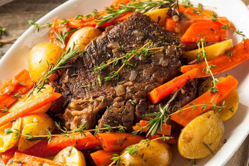 Crockpot pot roast with carrots and potatoes on a plate.
