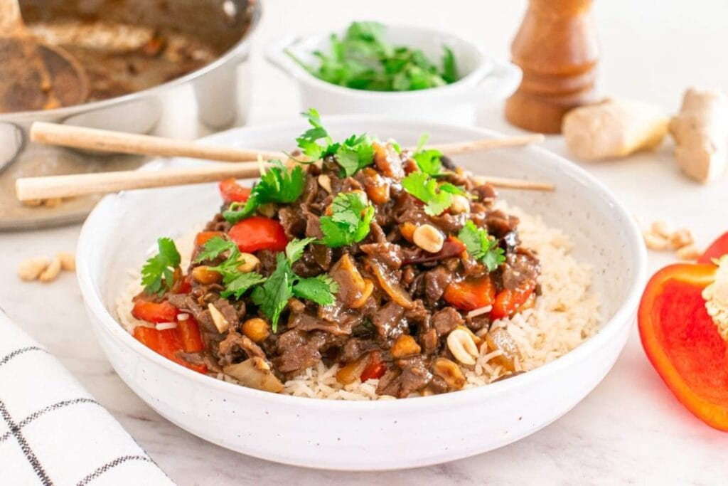 Kung pao beef served over rice on a plate.