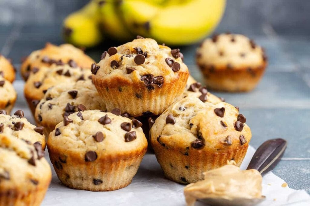 Peanut butter banana muffins with chocolate chips on parchment paper.