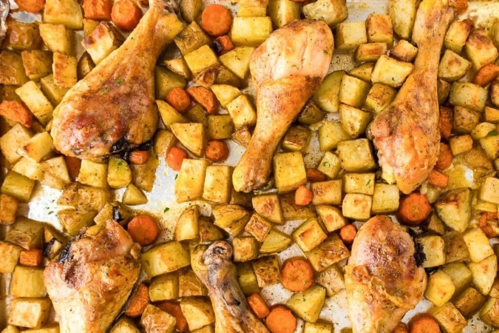 Sheet pan chicken drumsticks with roasted potatoes and carrots.