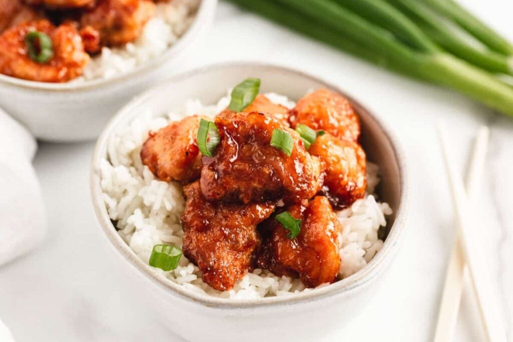 Sweet and sour chicken served over rice in a bowl.