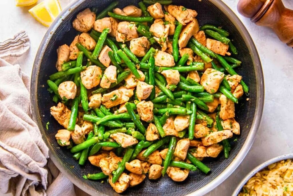 A close up shot of butter chicken and green beans.