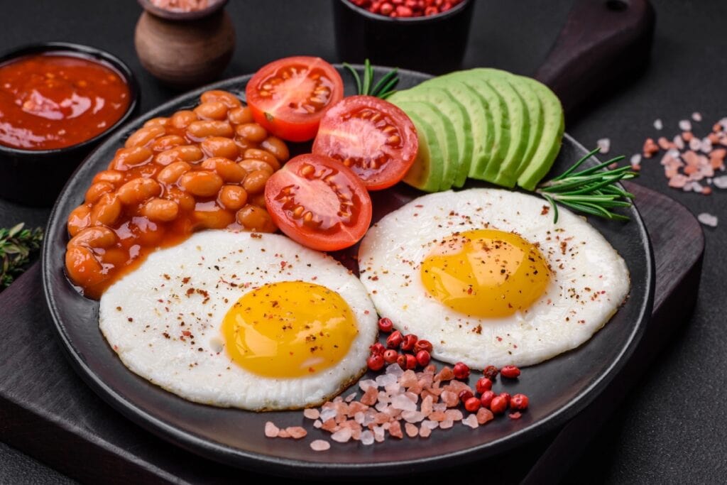 Fried eggs with baked beans on a plate.