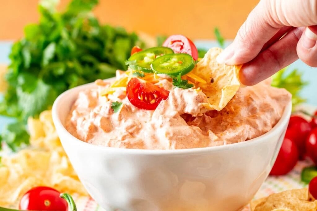 Creamy boat dip in a bowl with chips and jalape&ntilde;os.