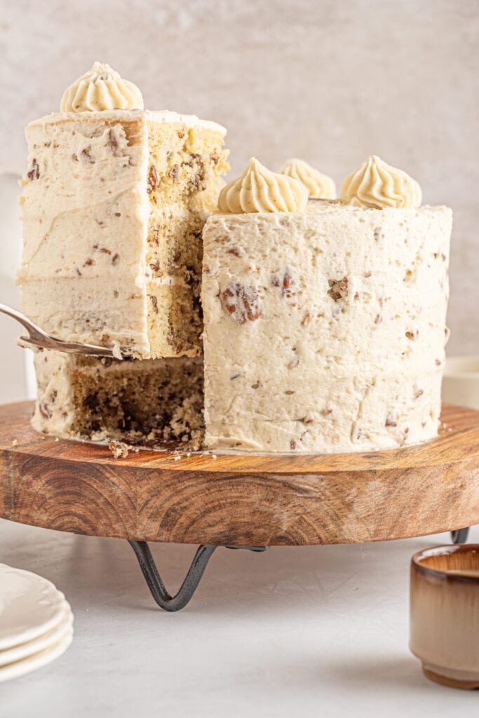 Butter pecan cake on a wooden cake stand.