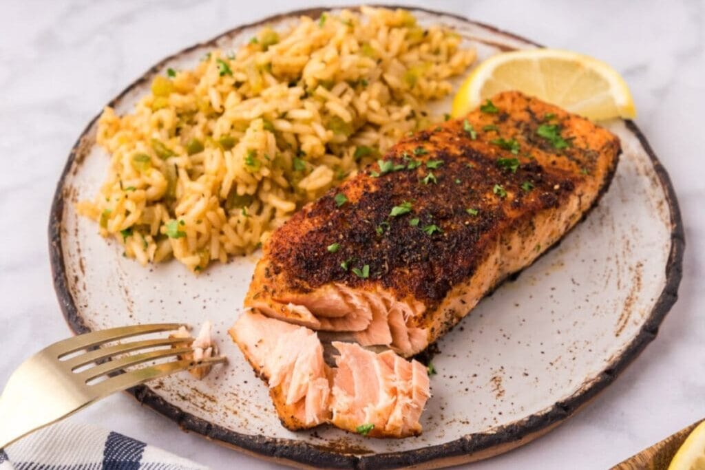 Cajun salmon with rice and lemon on a plate.
