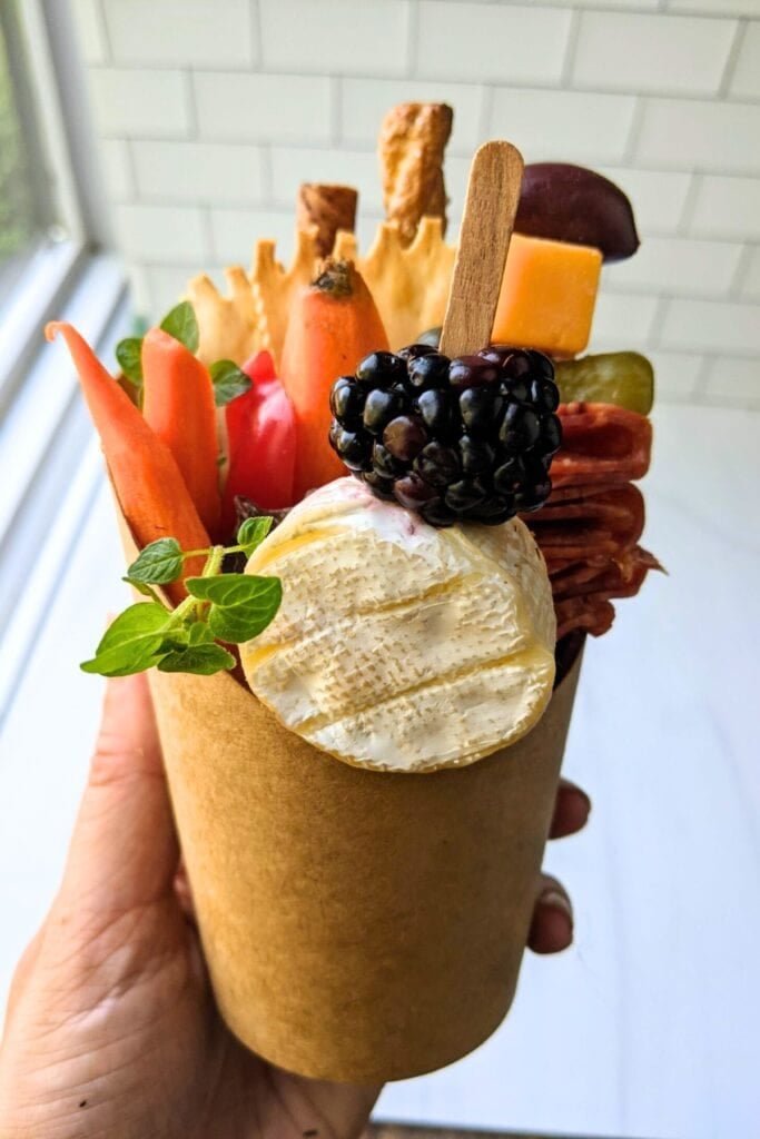 someone holding charcuterie cups
