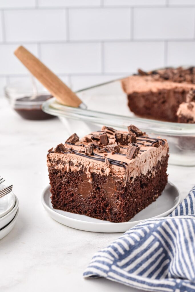 Slice of chocolate poke cake on a plate.
