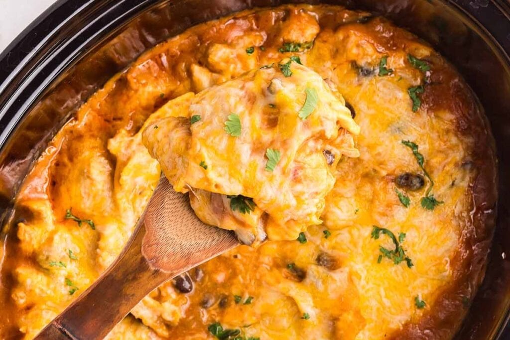 Crockpot chicken enchilada casserole on a wooden spoon.