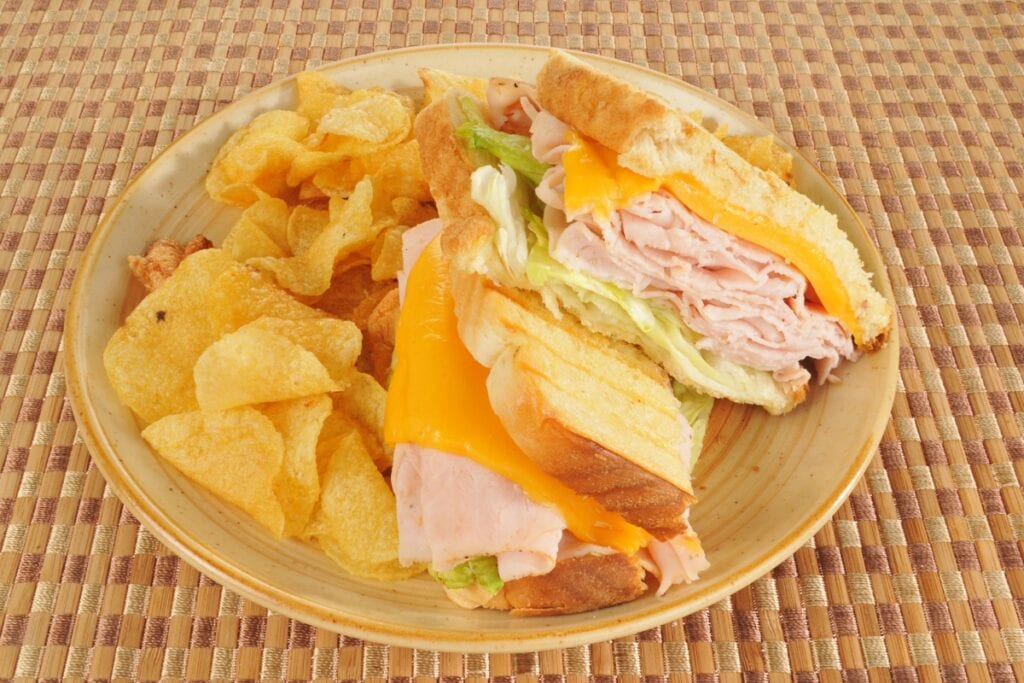 Deli sandwich and chips on a plate.