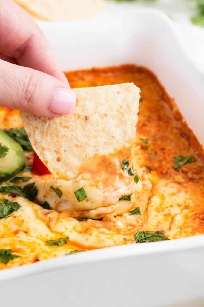 person scooping enchilada dip with chip