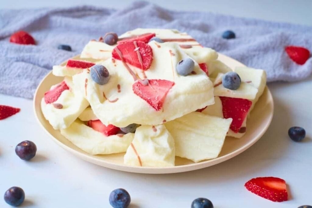 Frozen yogurt bark with berries and chocolate on a plate.