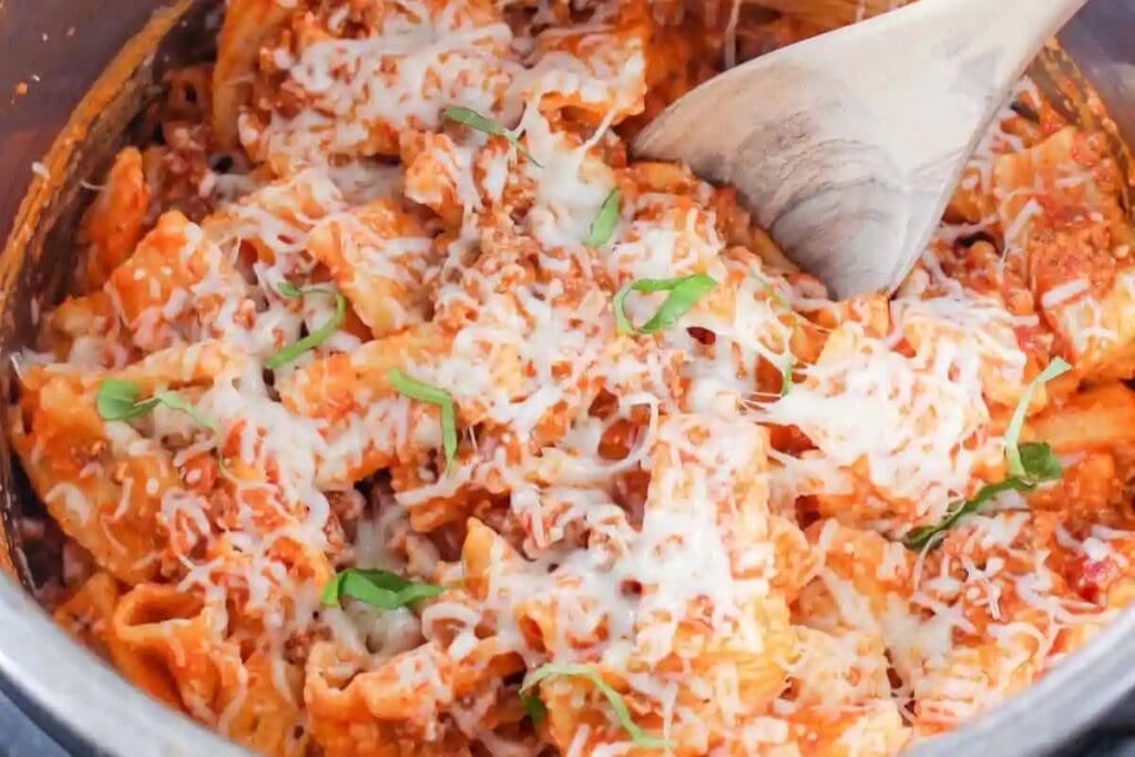 Rigatoni with meat sauce and melted cheese in a pot.