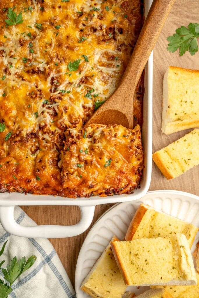 Italian noodle casserole in a baking dish with a wooden spoon.