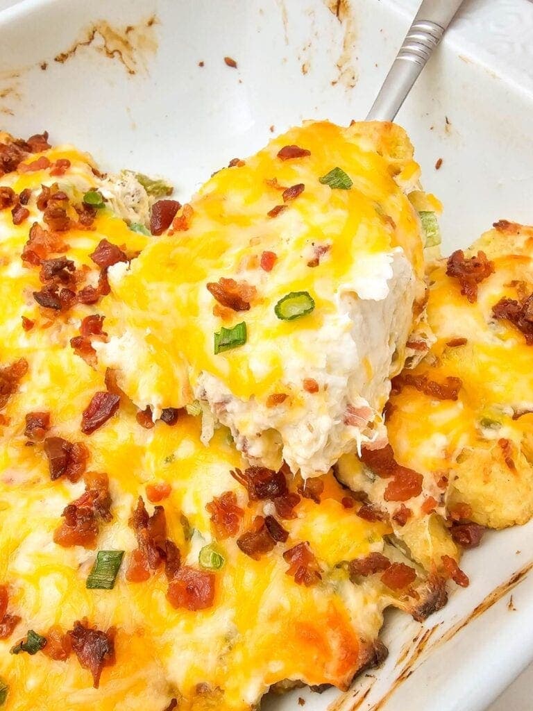 Close-up of creamy jalapeño popper chicken casserole on a serving spoon.