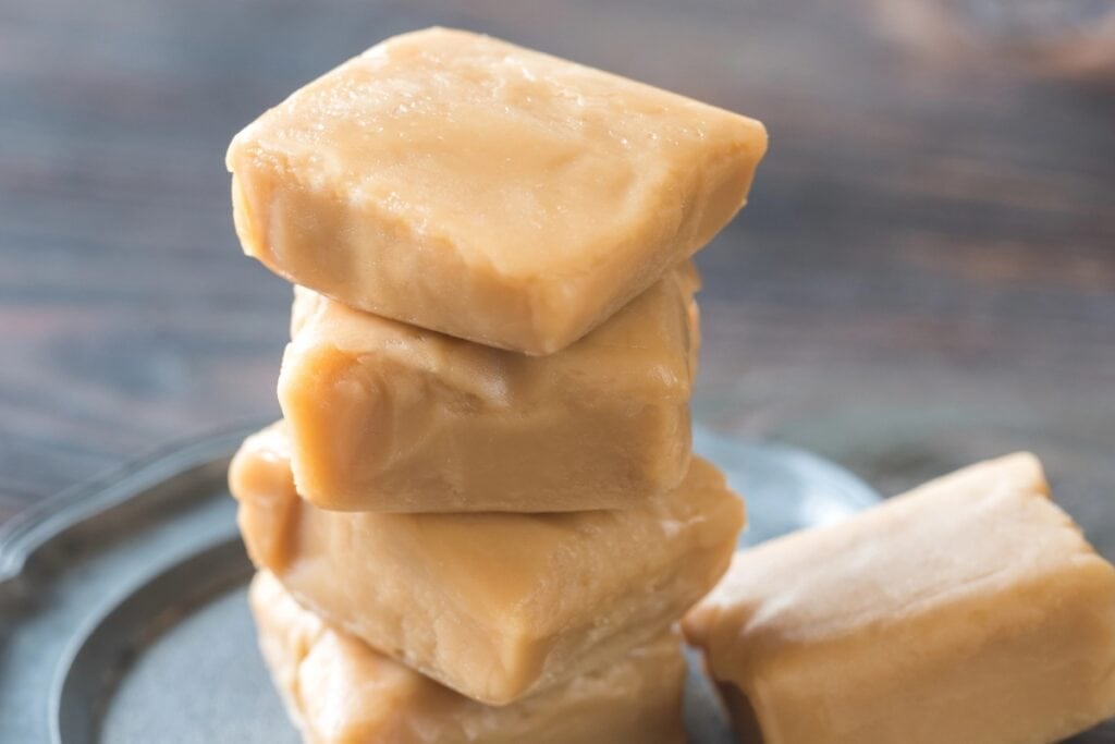 Maple fudge stacked on a plate.