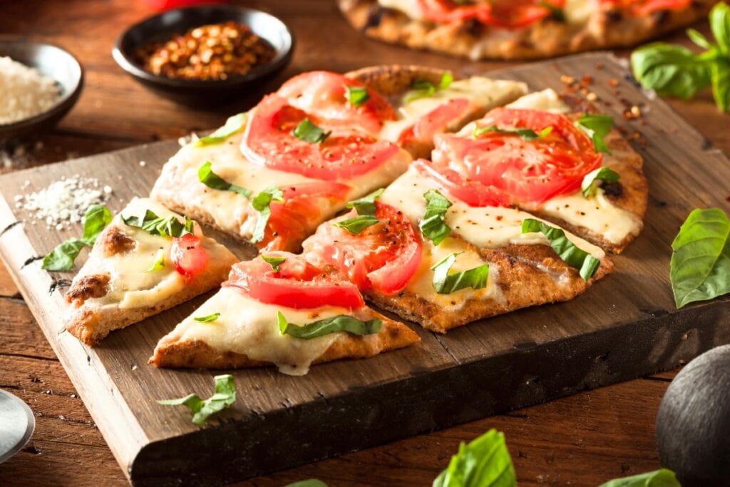 Naan pizza on a wooden board.