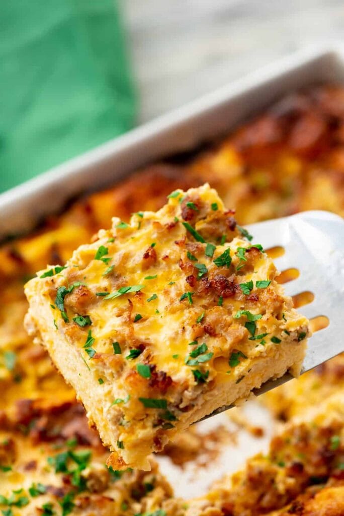 Slice of overnight sausage egg casserole on a spatula.