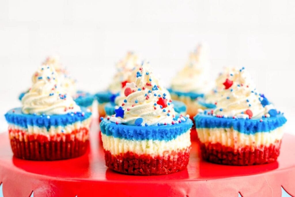 Red white and blue mini cheesecakes on a red table.
