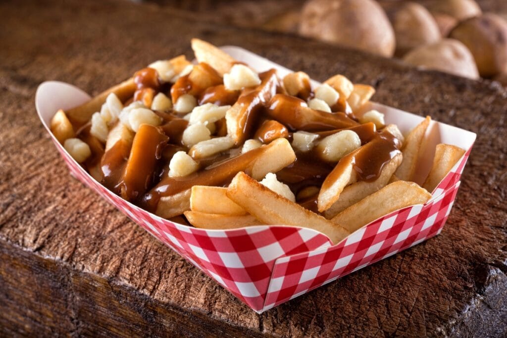 Poutine with gravy and cheese curds on a wooden table.