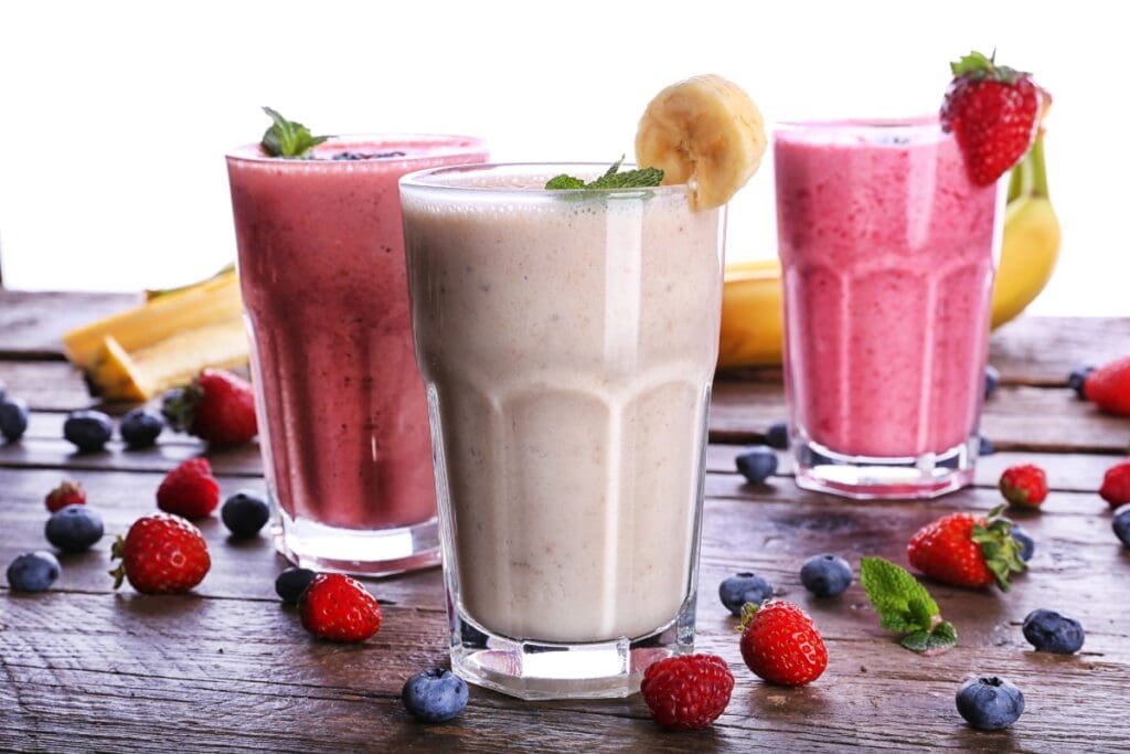 Protein shakes in glasses with fresh berries and banana.