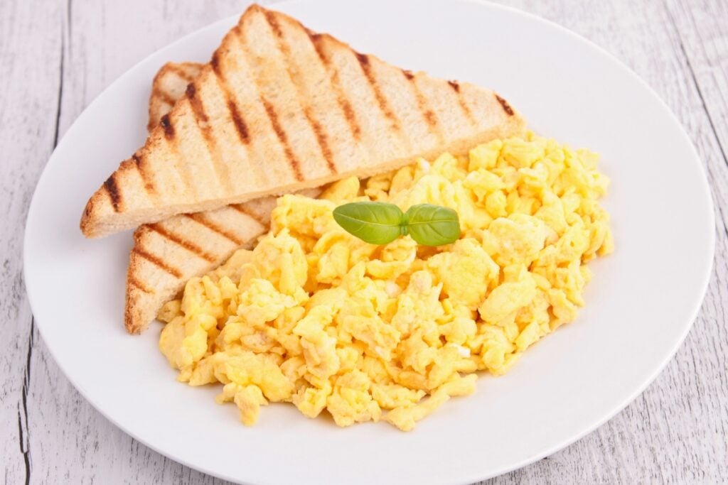 Scrambled eggs and toast on a plate.