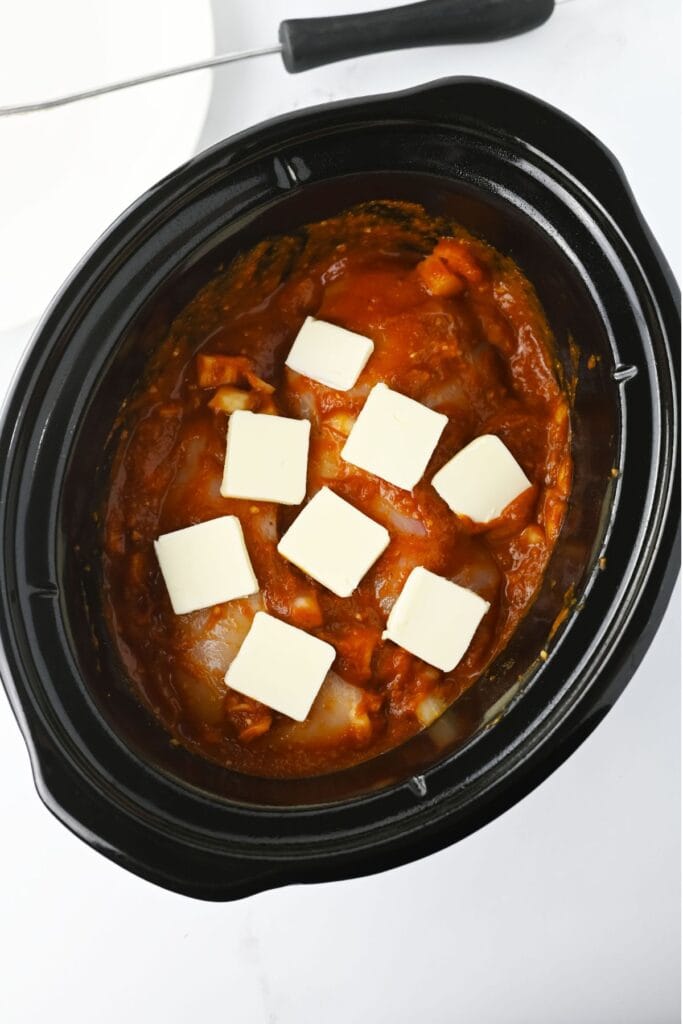 chicken in slow cooker with butter slices on top