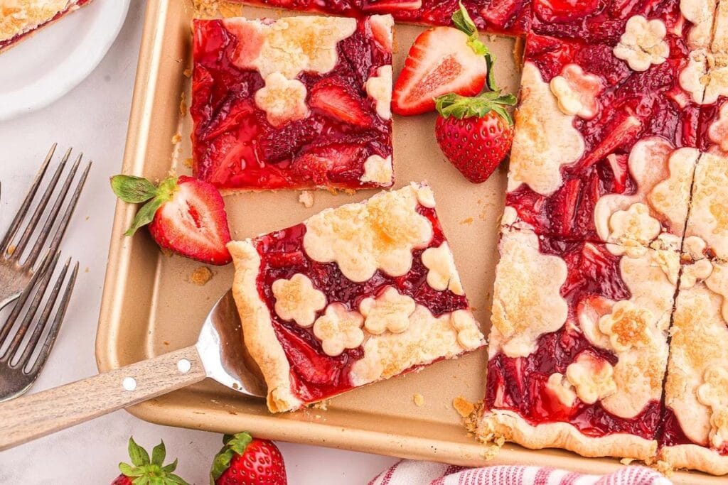 Strawberry slab pie sliced on a baking sheet.