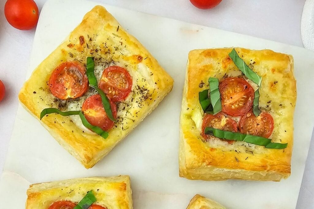 Tomato puff pastry tartlets on a plate.