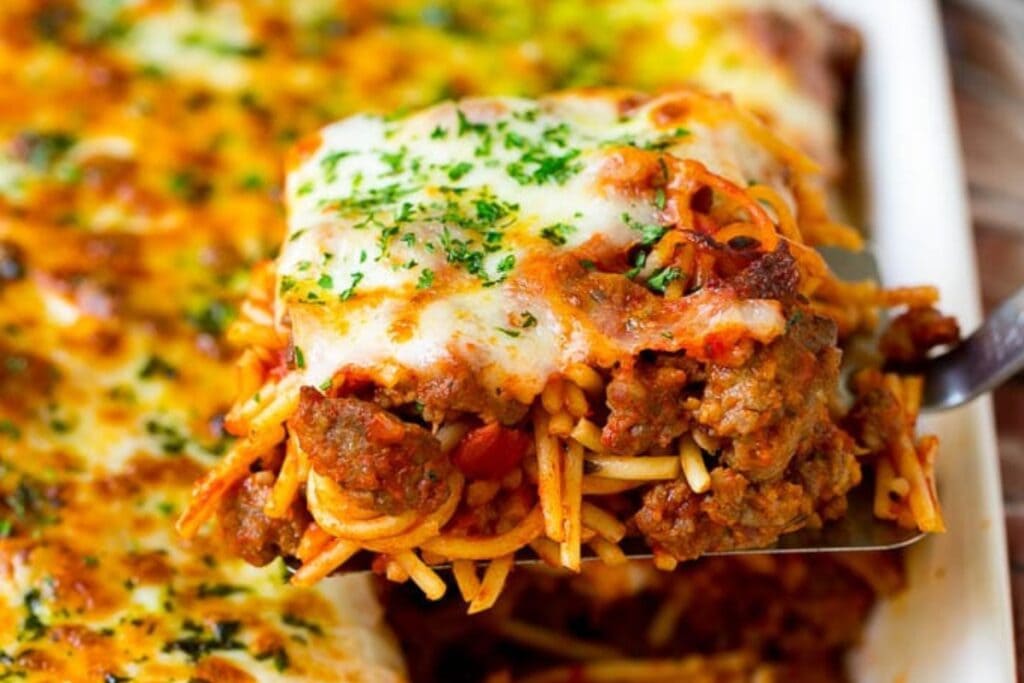 Close-up of baked spaghetti on a spatula with melted cheese.