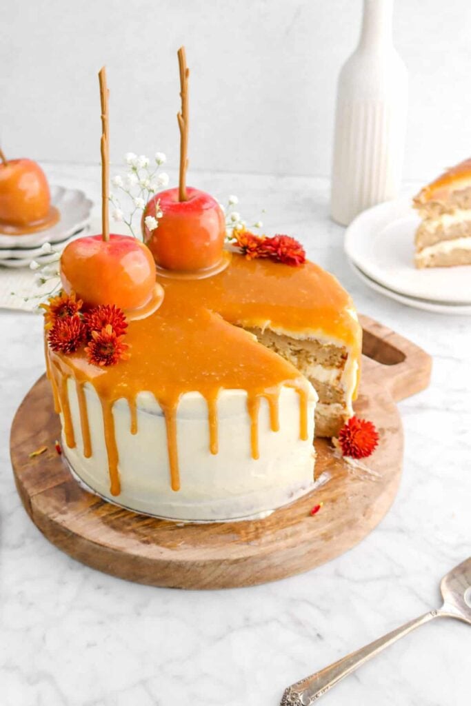 Caramel apple layer cake with caramel frosting on a wooden board.