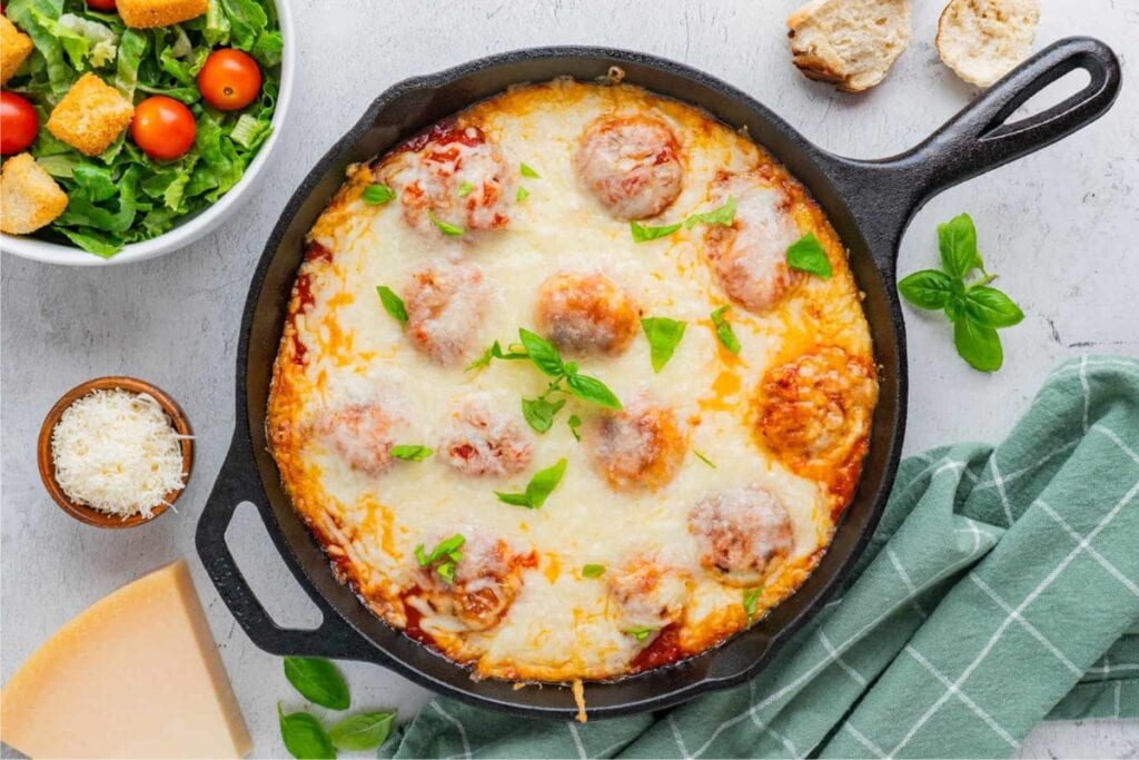 Chicken parmesan meatballs baked in a skillet.