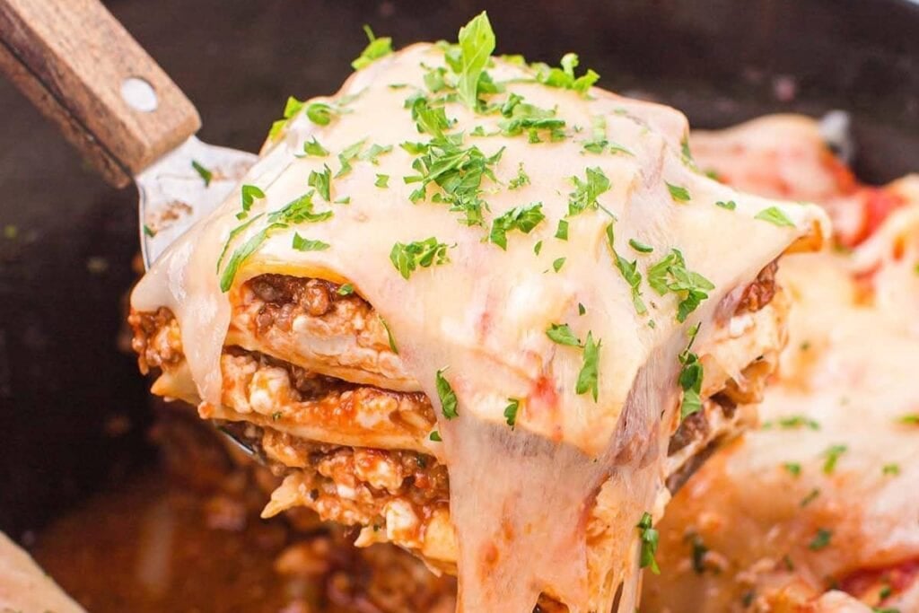 Close-up of crockpot lasagna on a spatula.