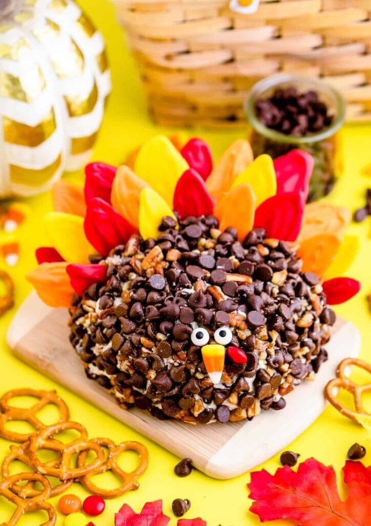 Turkey cheese ball decorated like a turkey on a wooden board.