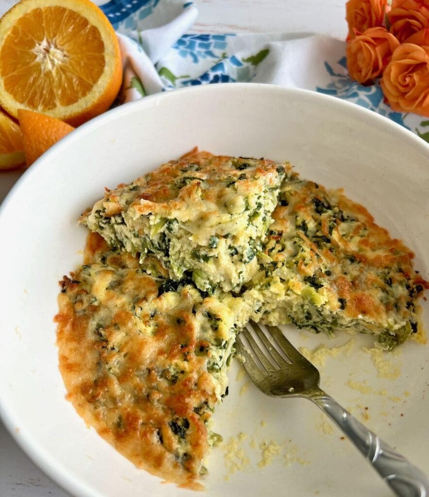 Air Fryer Quiche with spinach and cheese, partially sliced in a white dish.