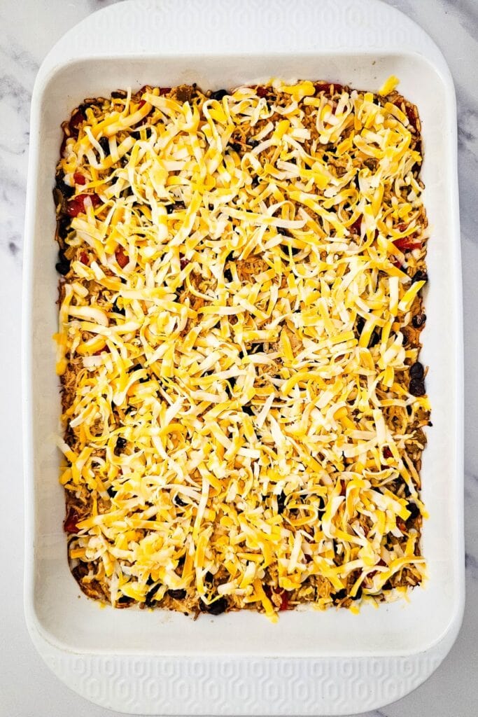 Chicken Taco Casserole topped with shredded cheese before baking.